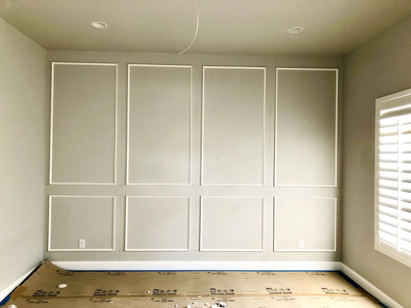 Wall panel molding installation in progress with floor protection in place