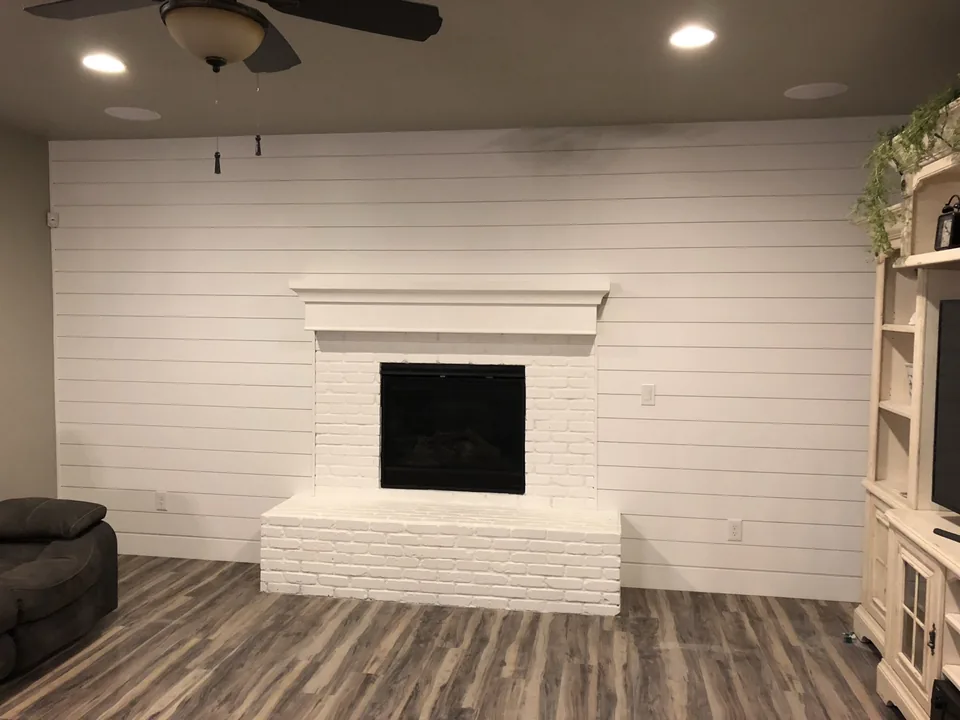 White shiplap wall surrounding a brick fireplace