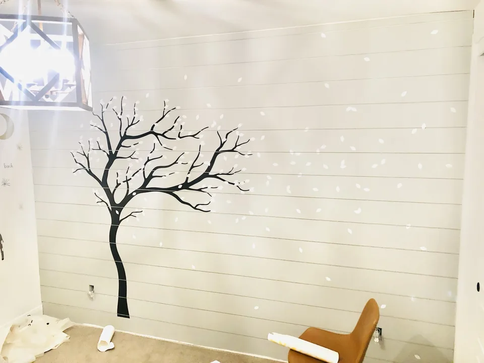 White shiplap wall with a decorative tree design during finishing