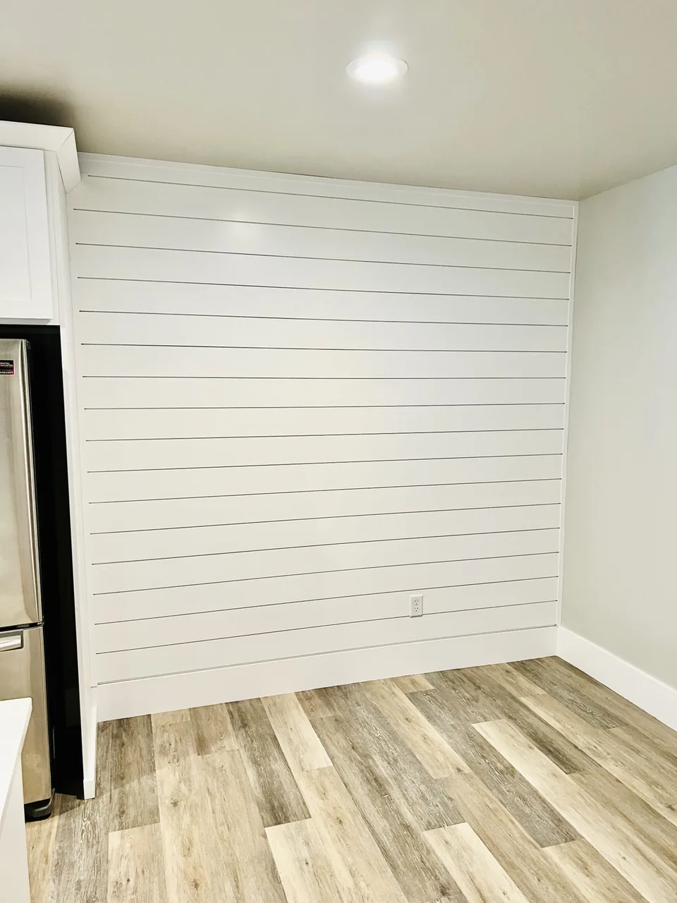 White shiplap accent wall beside a kitchen