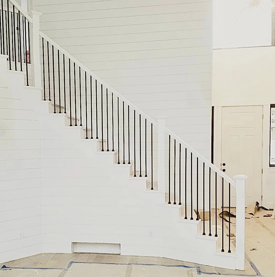 White horizontal shiplap behind a staircase with black balusters